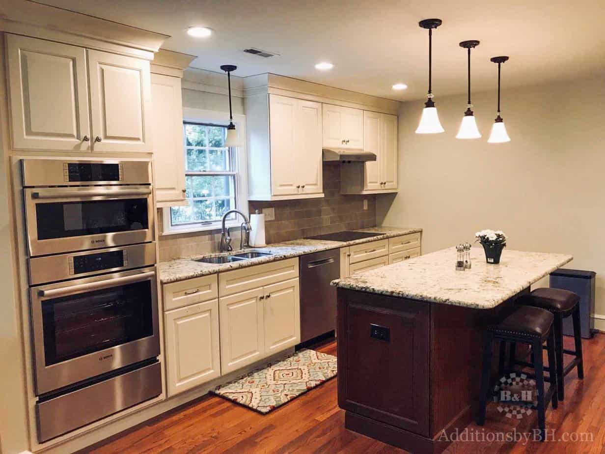A refinished kitchen with a granite island and counter tops, with our logo.