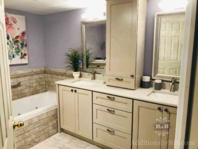 Remodeled bathroom with tan cabinets and tiling, with our logo.
