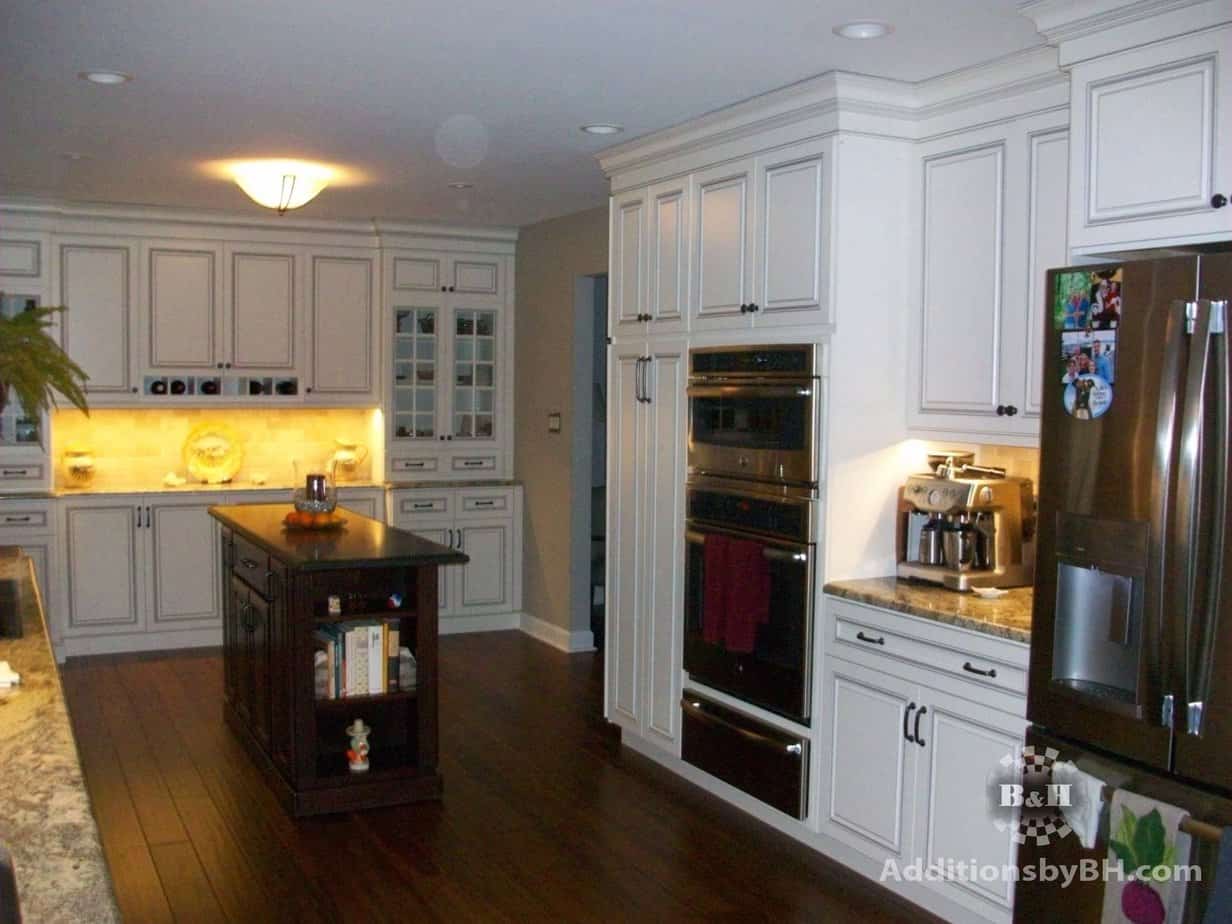 remodeled kitchen with backsplash, white cabinets, and a stainless steel fridge, with our logo.