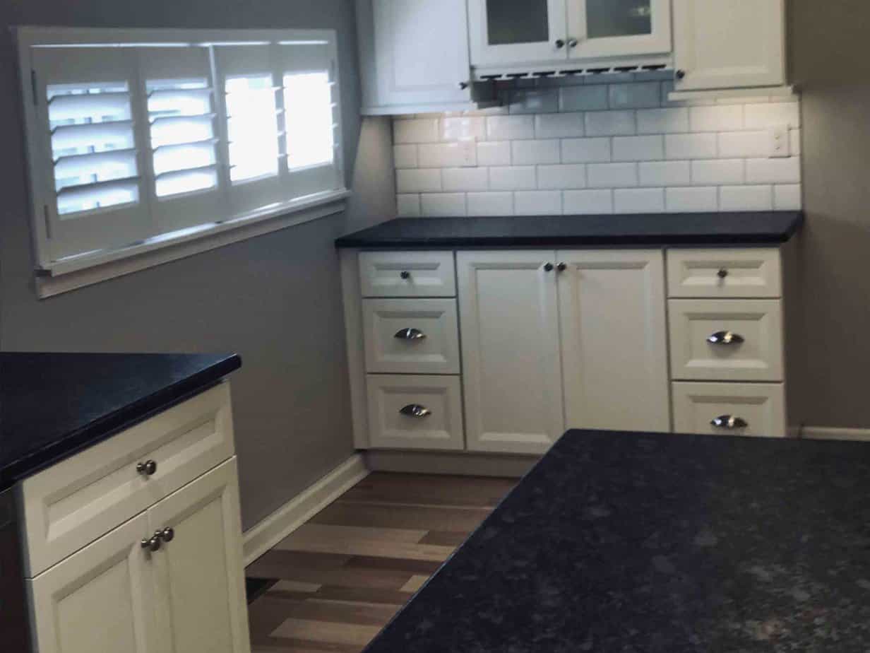 Refinished kitchen with a small window and black counter tops.