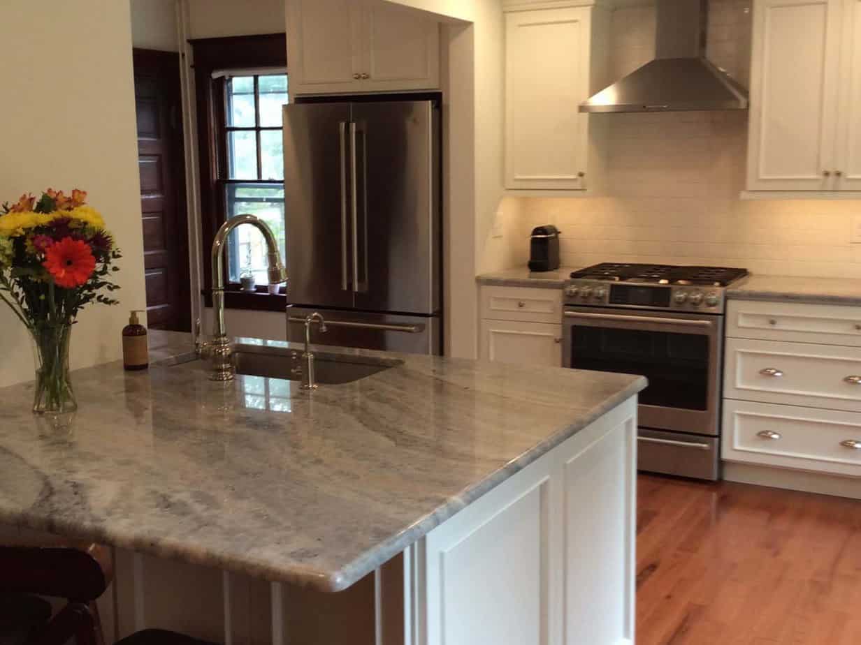 A refinished kitchen with a large granite counter top.