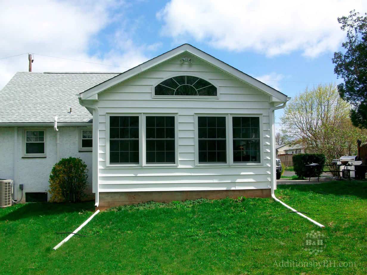 A home addition with two white rain gutters on the sides, with our company logo.