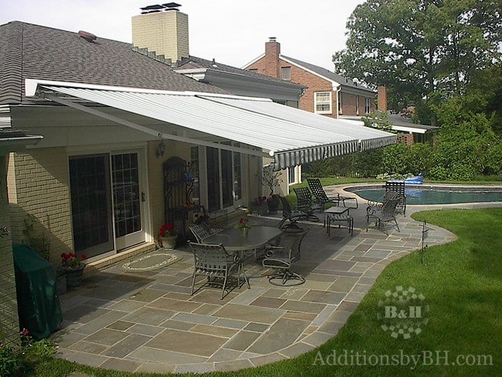 Outdoor awning covering a stone slab patio, with our logo.