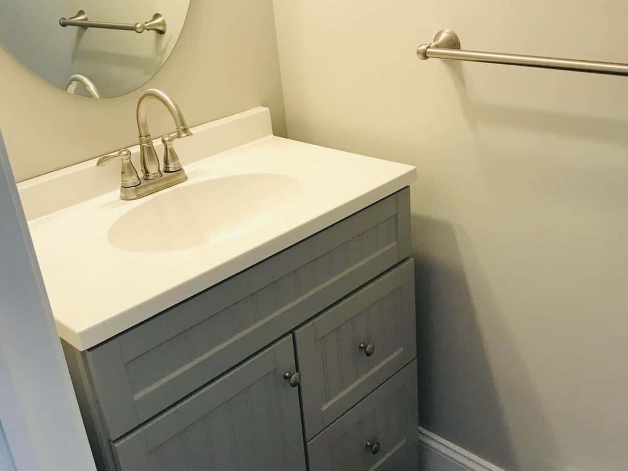 Remodeled bathroom sink with grey cabinet.