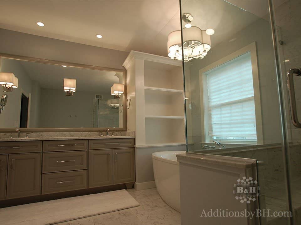 A refinished bathroom with tan cabinets and two sinks, with our logo.