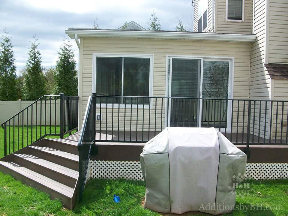 A finished wooden deck with a covered grill in front of it, with our company logo.