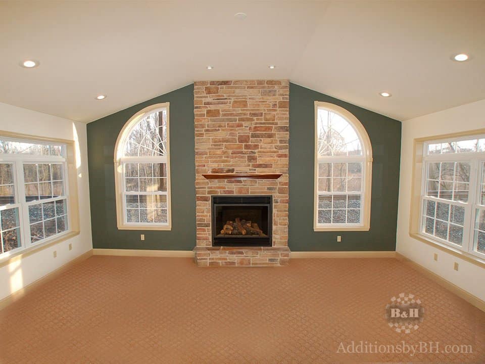 A home addition with a brick fireplace, with our company logo.