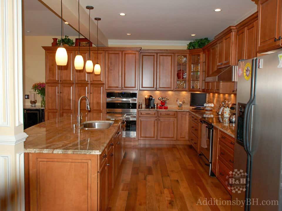 Refinished kitchen with wood flooring and cabinets and island, with our logo.
