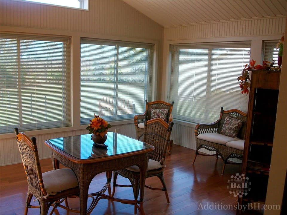 New sunroom with large windows and blinds, with our logo.